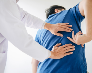 man being checked by a doctor for his back pain after a car accident